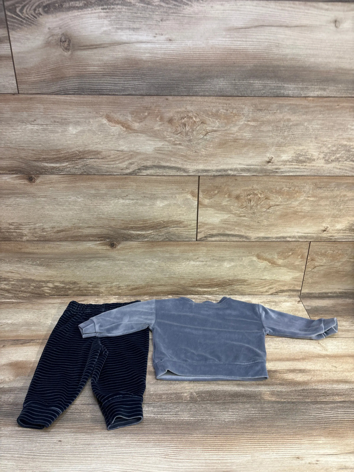 Flat lay of Carter’s 2-piece grey velour shirt and dark striped velour pants showing soft velour texture on wood background