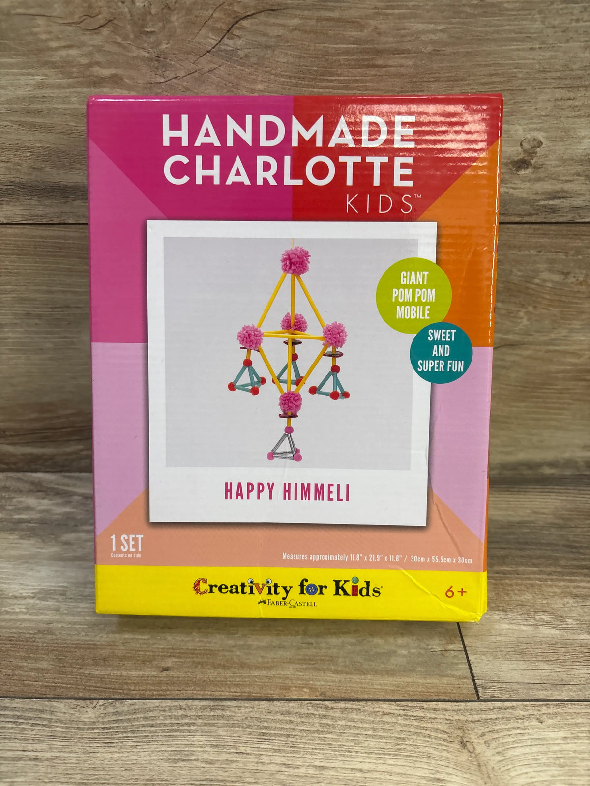 Front view of Handmade Charlotte Kids Happy Himmeli craft kit packaging showcasing a giant pom pom mobile