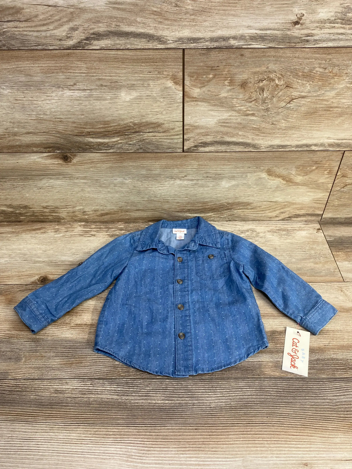 Flat lay of Cat & Jack toddler button-up denim shirt showing long sleeves, front buttons and chest pocket on wood background