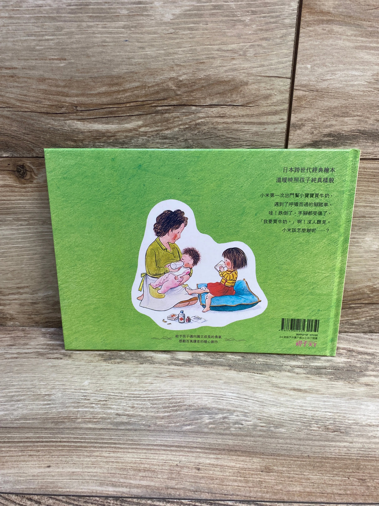 Back cover of Go Shopping for the First Time Chinese hardcover book showing green background, illustration of a parent feeding two kids, and Chinese text