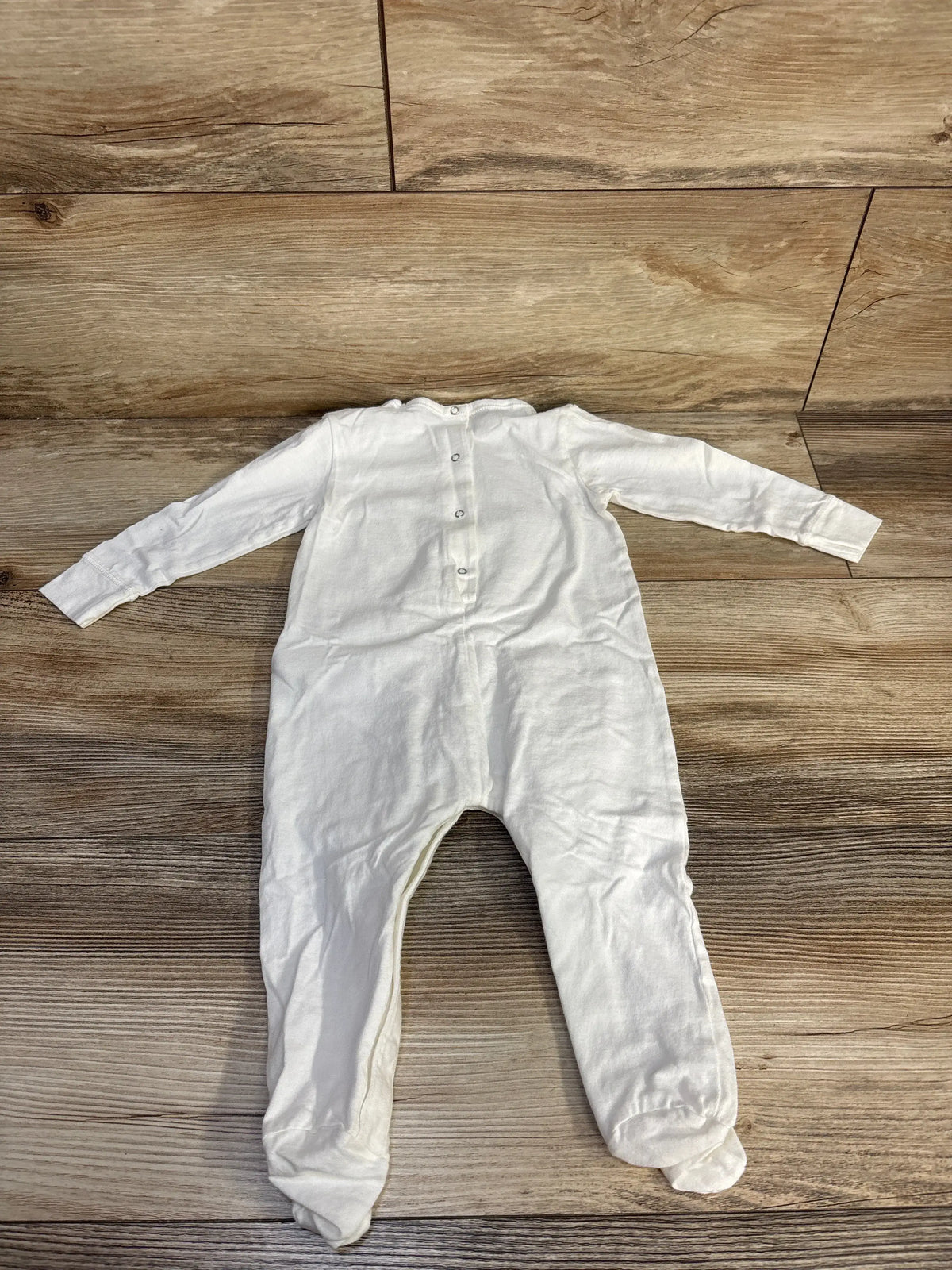 Front view of Gucci cotton logo footie sleeper in white showcasing long sleeves, snap front, and enclosed feet on wood floor