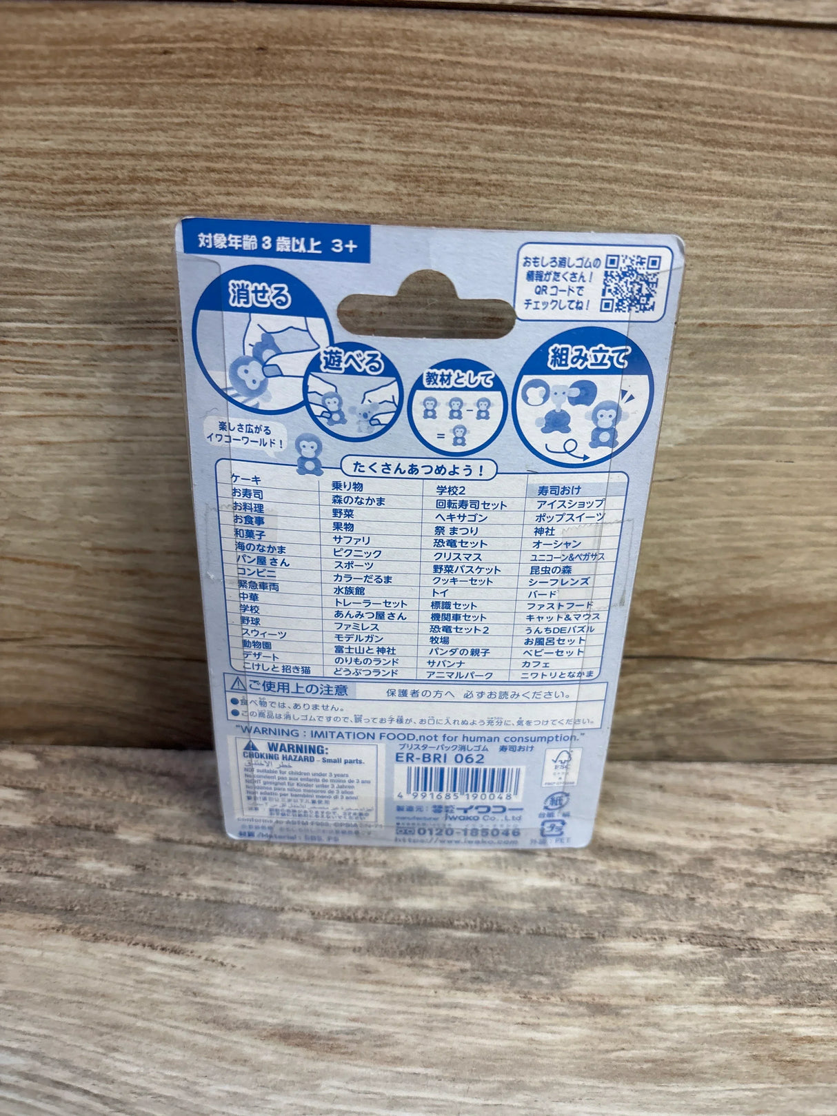 Back view of NEW IWAKO sushi eraser set showing packaging back with Japanese illustrations and barcode on wood background