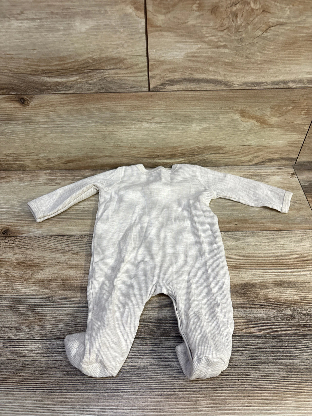 Flat lay of Koala Baby waffle-knit snap sleeper showing waffle texture, long sleeves, and footed legs on wood background