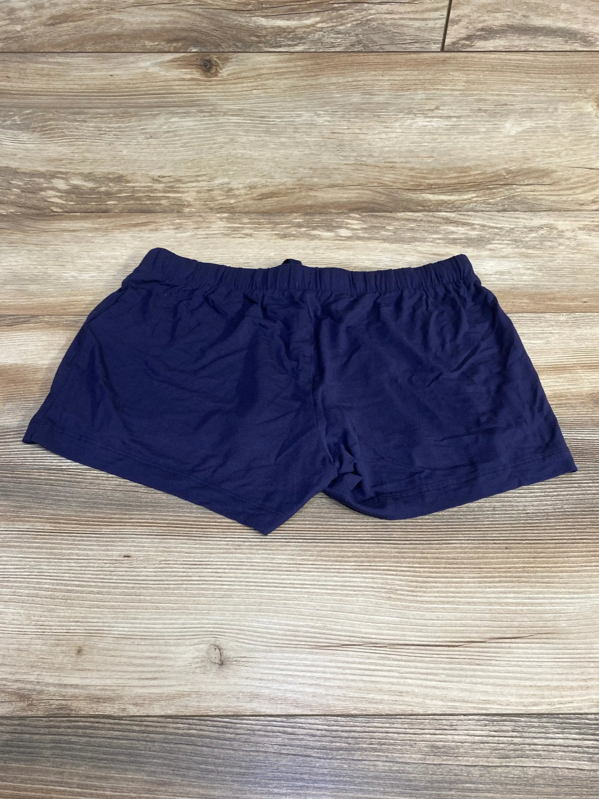 Flat lay of navy Gap Body maternity modal shorts showing elastic waistband and short inseam on light wood background