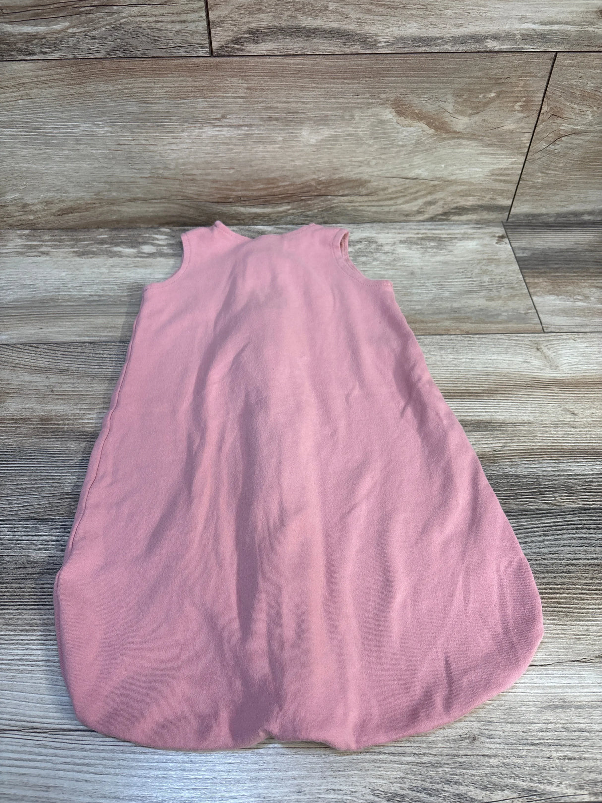 Pink sleeveless baby sleep sack on wood floor, soft cotton kids sleepwear for infants