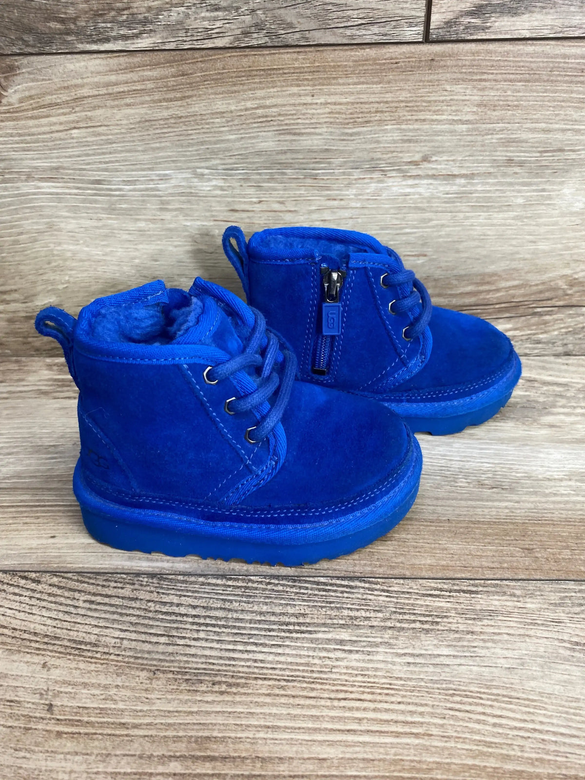 Bright blue suede toddler boots with laces and side zipper on wooden background