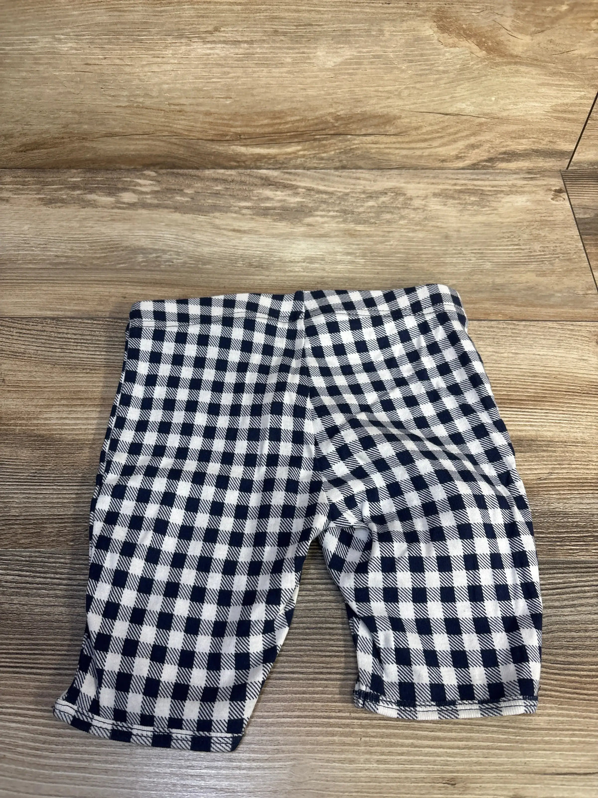 Flat lay of Old Navy toddler bike shorts in navy and white gingham showing elastic waistband and mid-thigh length on wood background