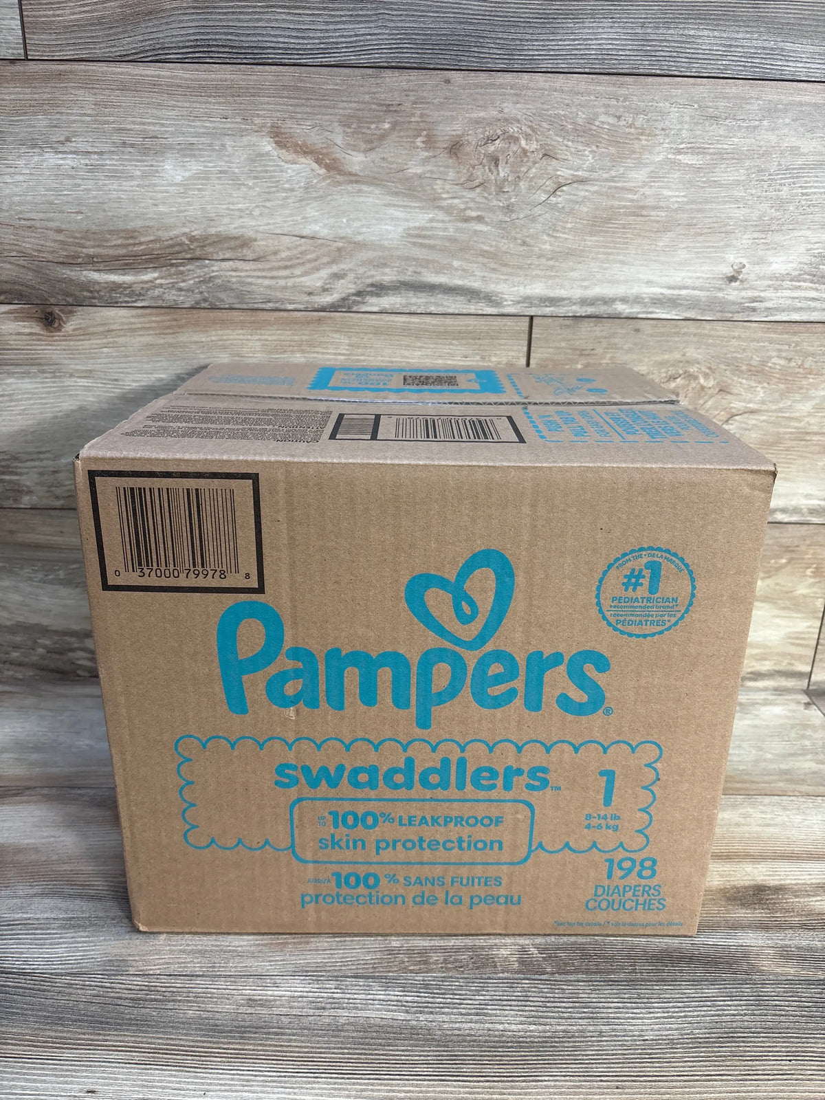 Front view of Pampers Swaddlers diapers box showing 100% leakproof skin protection, size 1, and 198 diapers on a wood backdrop