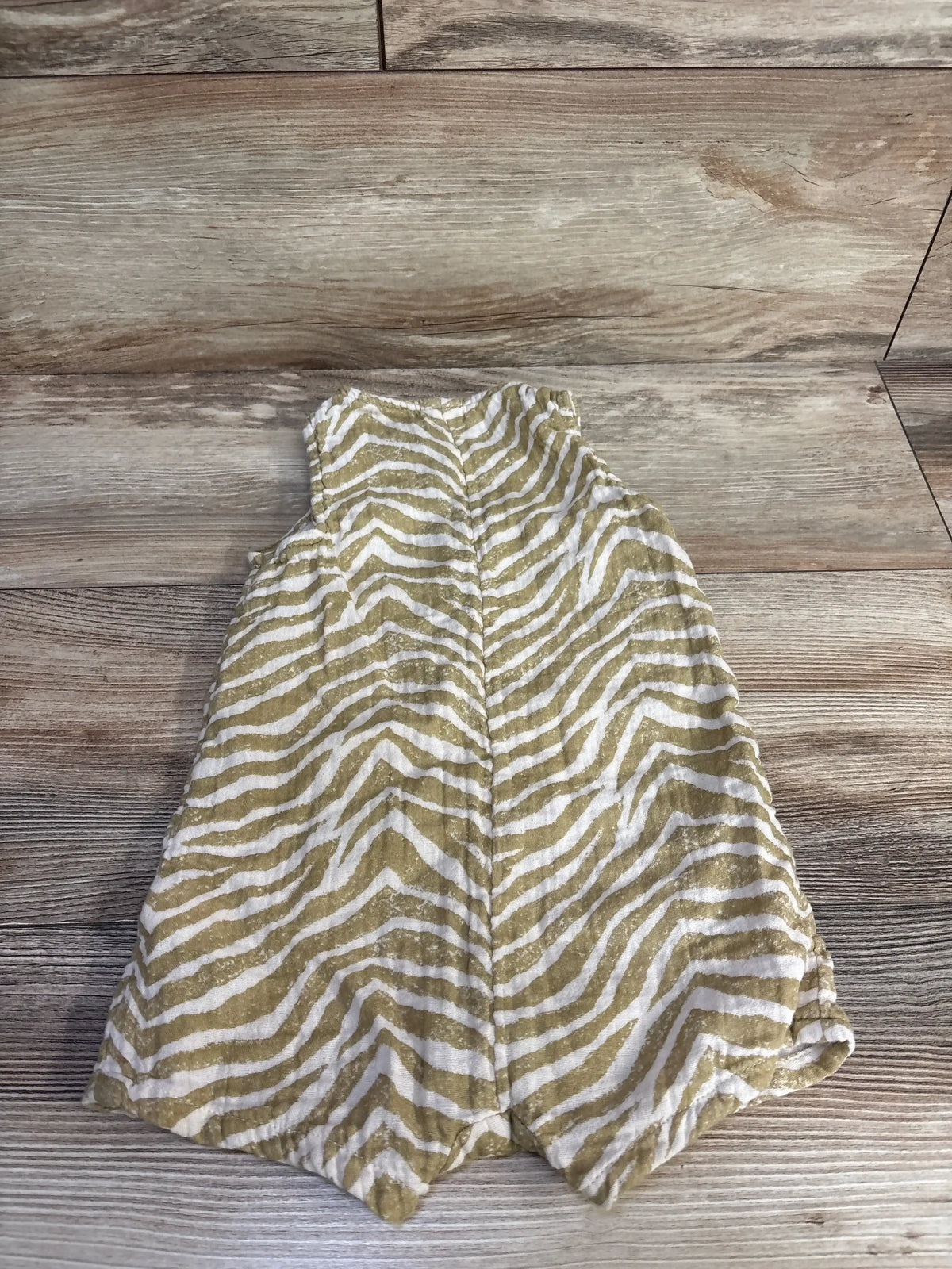 Back view of Old Navy sleeveless double-weave henley romper showcasing tan zebra print on a wood-look floor