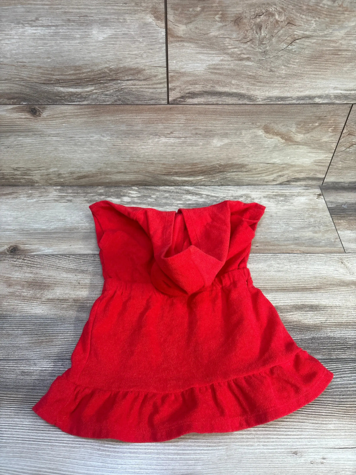 Top-down view of red Minnie Mouse terry swim cover-up (2T) showing hood, elastic waist, and ruffle hem on wood background