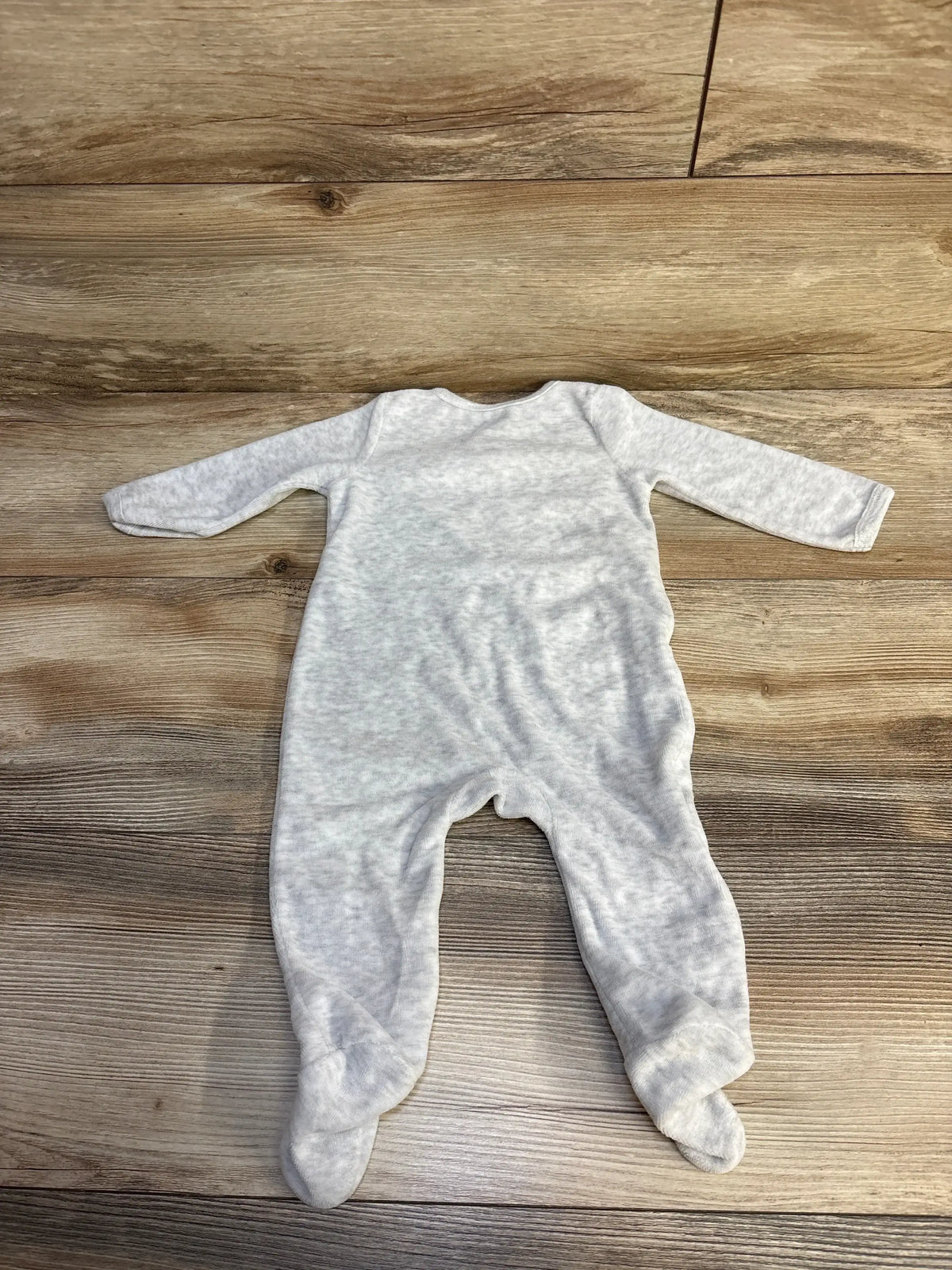 Soft gray baby footed sleeper lying flat on wooden floor