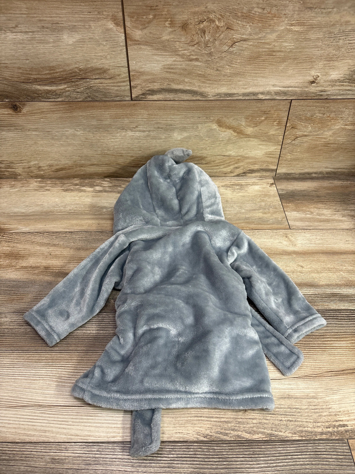 Top view of a grey Hudson Baby shark plush hooded robe for 0 to 9 months, showing its hood and sleeves on a wood look floor