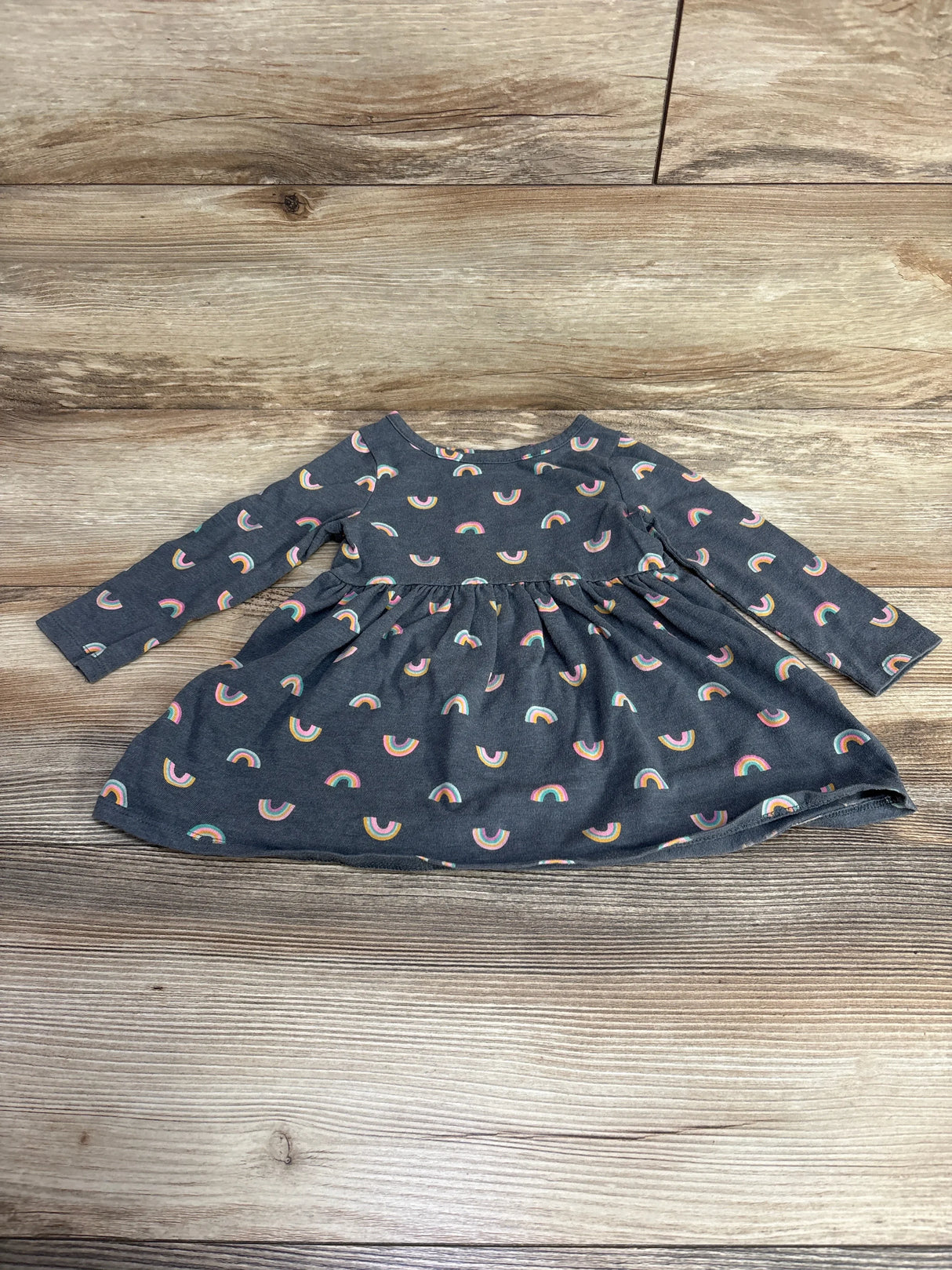 Dark gray long-sleeve baby dress with colorful rainbow patterns on wooden background