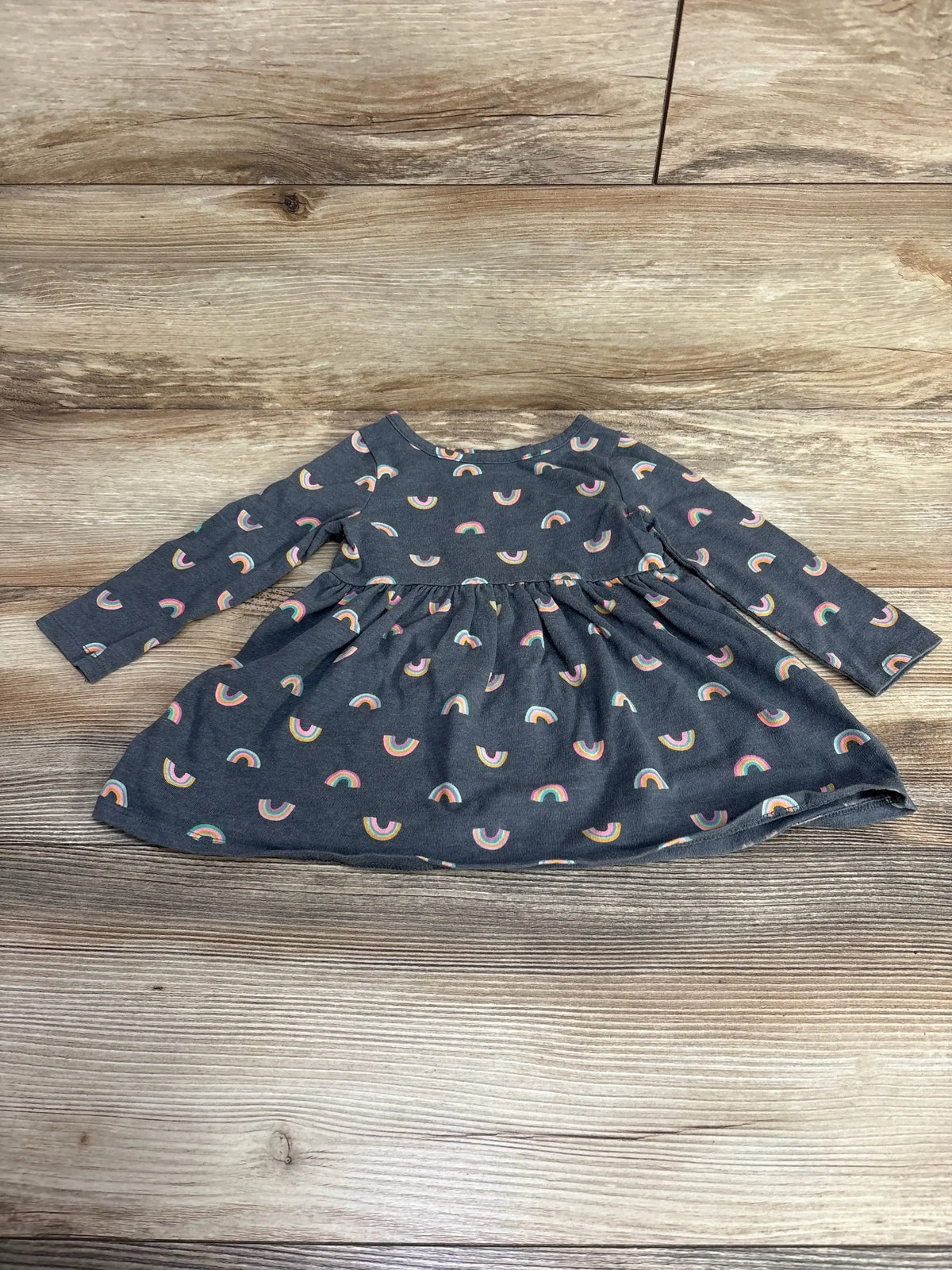 Dark gray long-sleeve baby dress with colorful rainbow patterns on wooden background