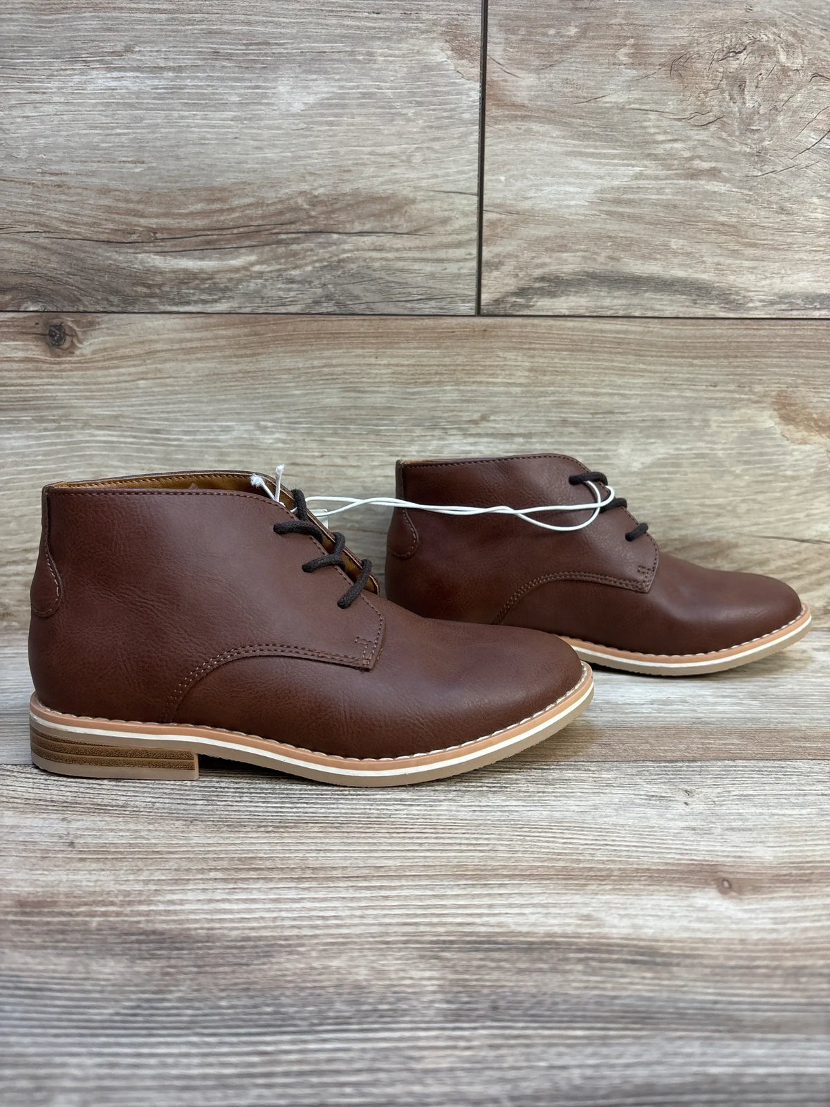 Brown leather kids lace-up dress boots with rubber soles on wood floor