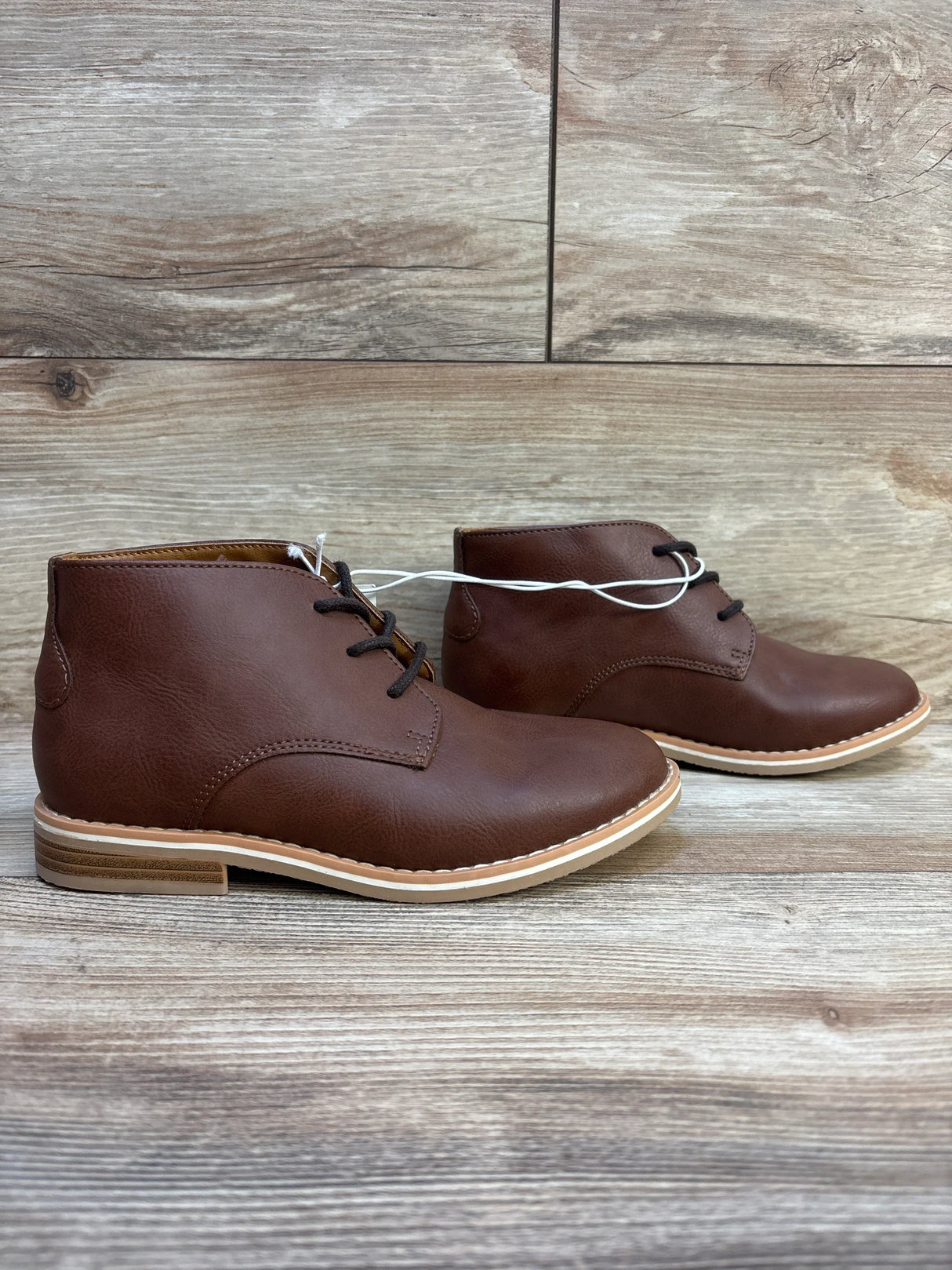 Brown leather kids lace-up dress boots with rubber soles on wood floor