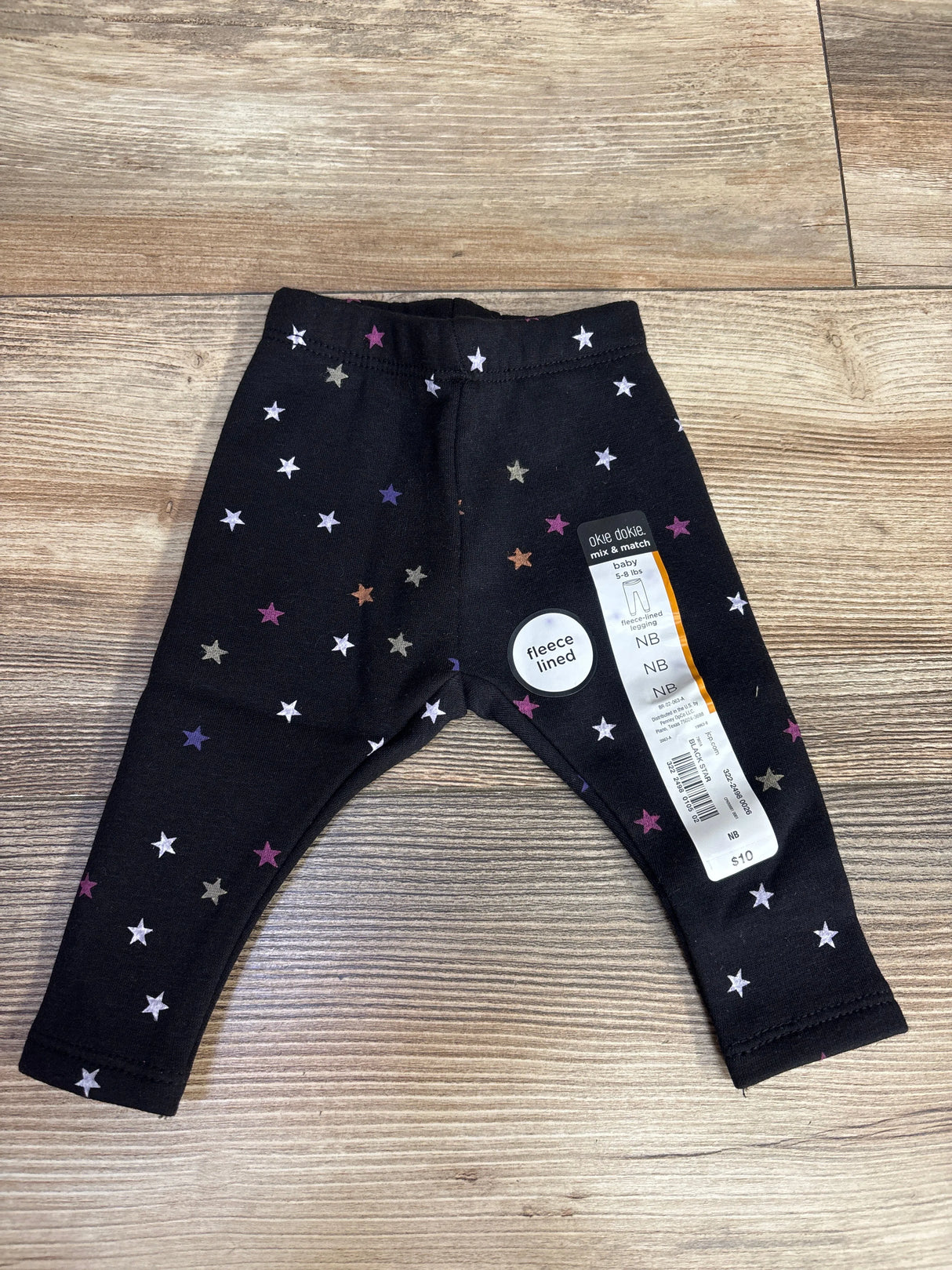 Black fleece-lined baby leggings with multicolor star patterns, size NB, priced at $10