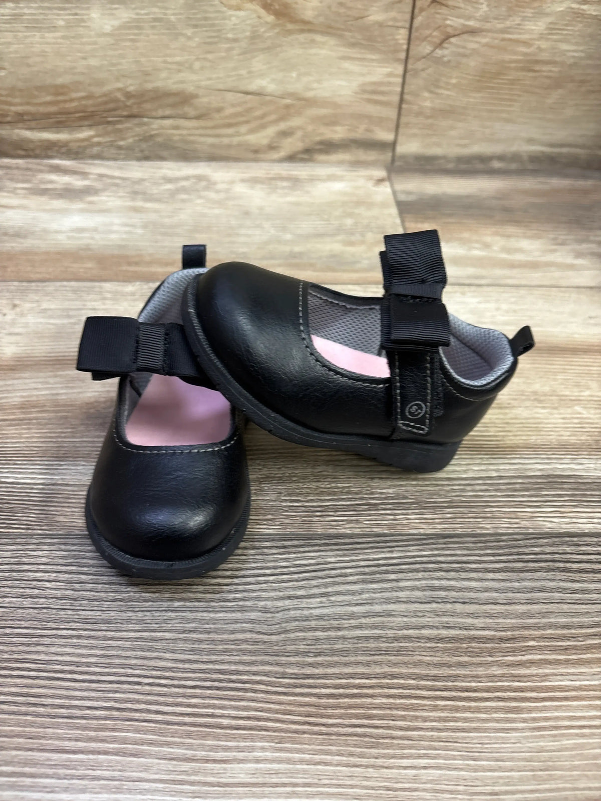 Top and side view of black Stride Rite 360 Hazel Mary Jane flats showing Mary Jane straps and pink lining on a wood-grain surface