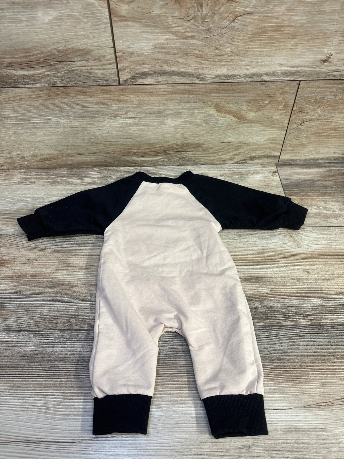 Flat lay of Lamuusaa Mama’s Little Boo coverall with black sleeves and cuffs, size 0-3 months, on wood-patterned flooring