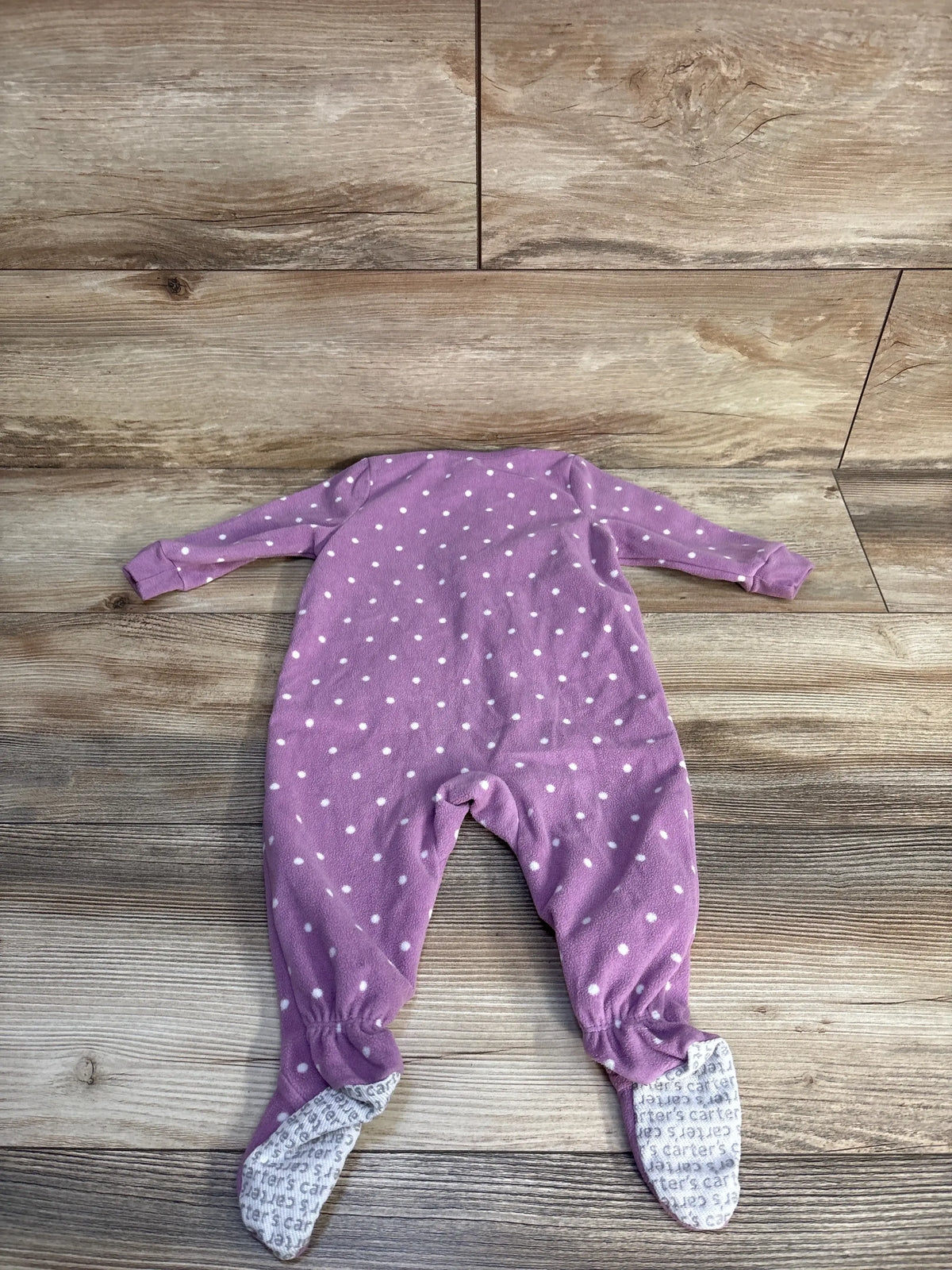 Front view of Carter’s purple blanket sleeper with white polka dots and covered feet on a wood-look background