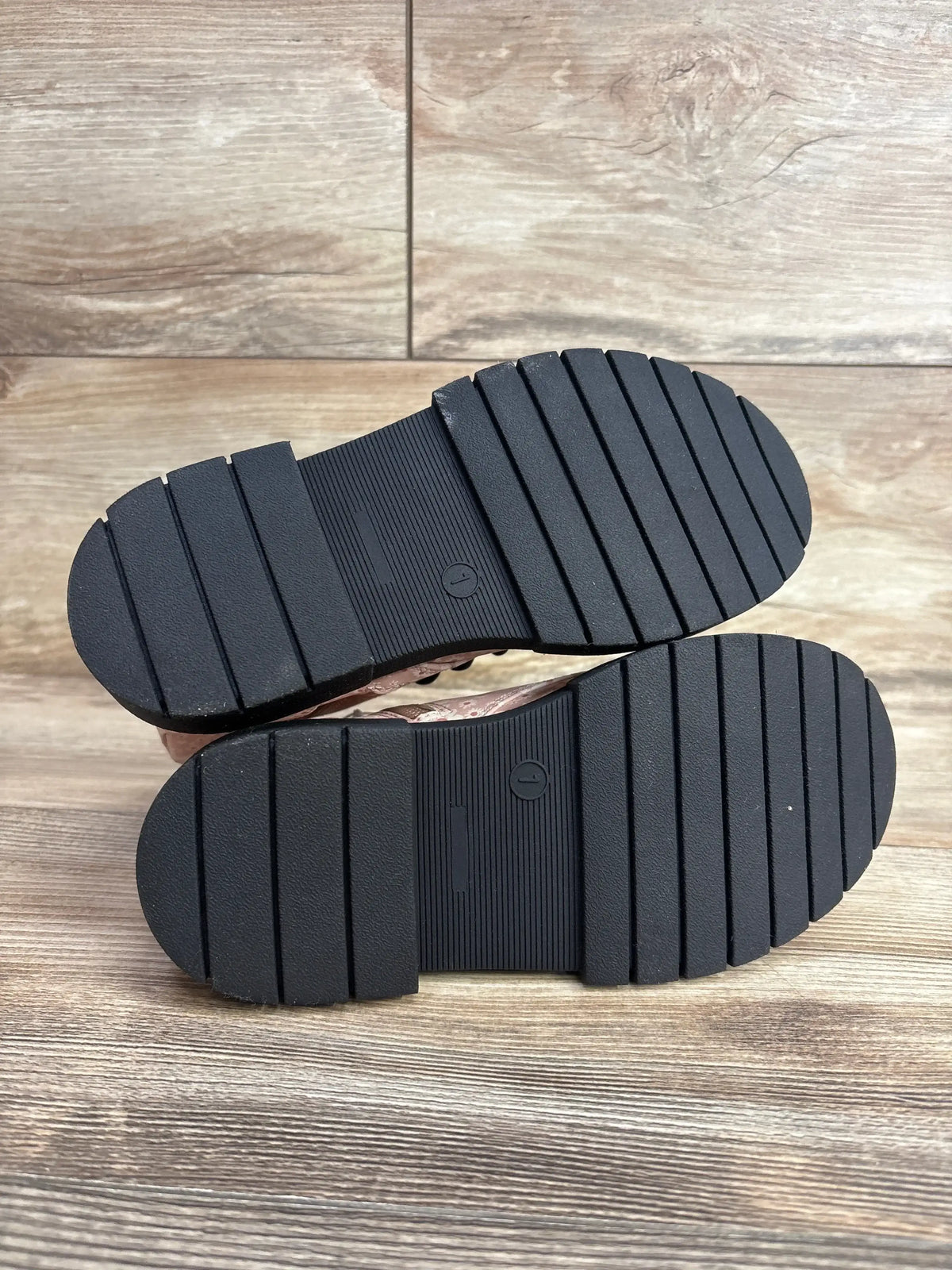 Bottom view of NEW Art Class Kayden boots size 1Y showcasing black grooved non-slip soles on wood floor background