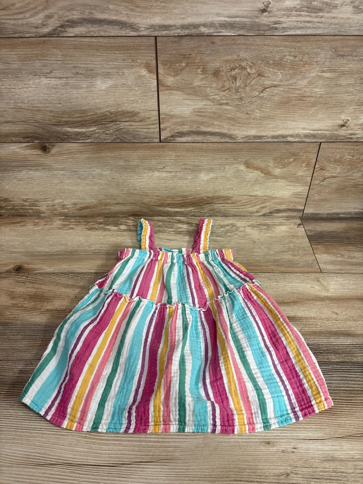 Front view of Cat & Jack muslin tank dress, size 2T, showcasing colorful vertical stripes and tiered skirt on a wood floor
