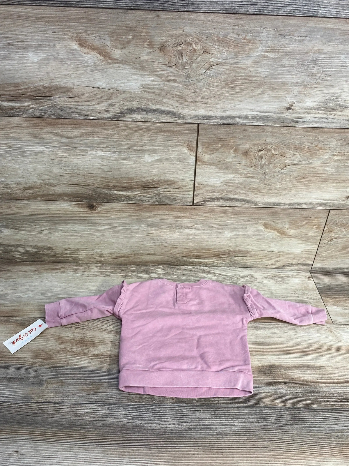 Pink long sleeve toddler shirt with ruffle details on wooden background