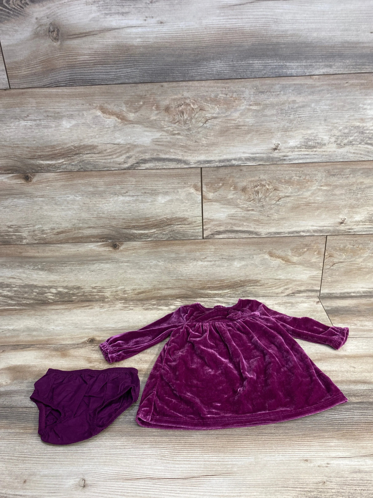 Purple velvet baby dress and matching diaper cover on wood background, kids clothing set