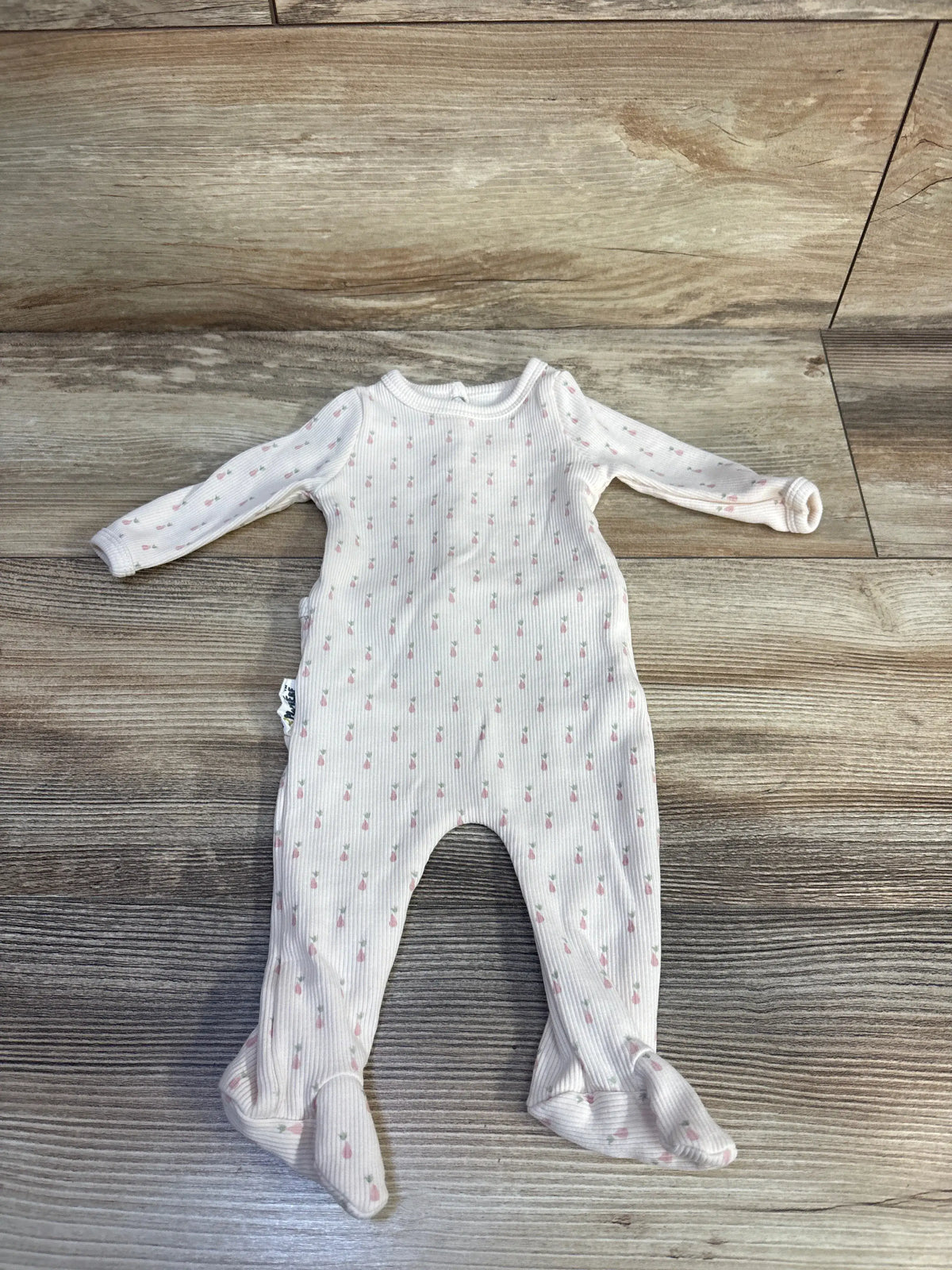 Front view of Maniere ribbed footie sleeper showcasing long sleeves, enclosed feet, and patterned ivory fabric on a wood floor