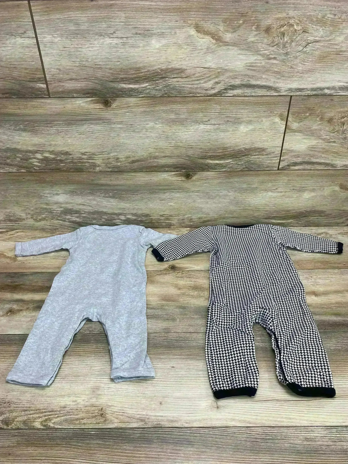 Flat lay of Hudson Baby 2-pack coveralls (3-6 mo) showing a solid gray and a black-and-white houndstooth set on light wood floor