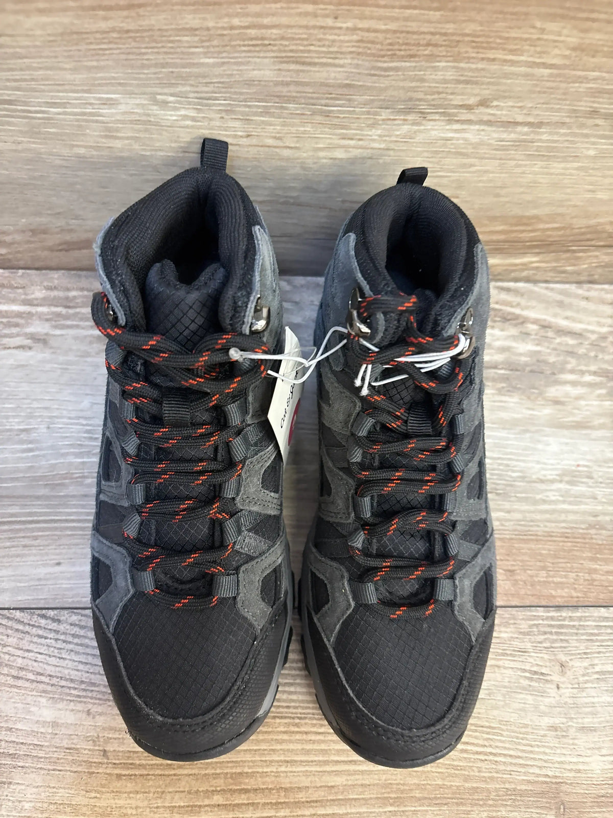 Pair of black and gray kids' hiking boots with red-accented laces on wood floor