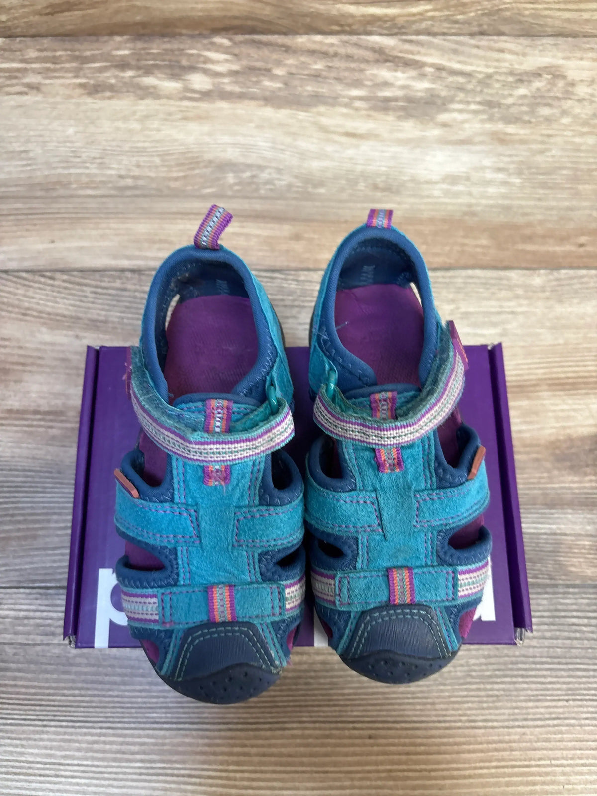 Top view of Pediped Flex Sahara sandals size 6/7c, teal-blue and purple closed-toe sandals with striped Velcro straps on a purple box