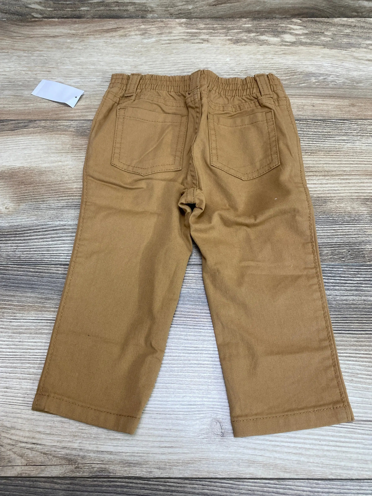 Back view of Old Navy 360-degree stretch skinny toddler pants showcasing elastic waistband and two back patch pockets on light wood background