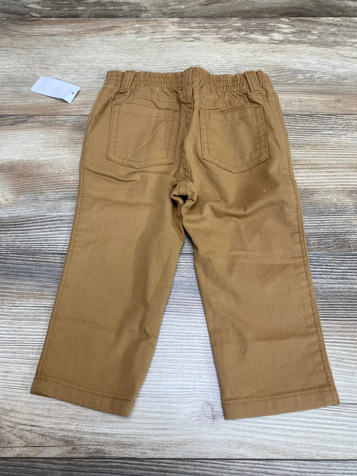 Back view of Old Navy 360-degree stretch skinny toddler pants showcasing elastic waistband and two back patch pockets on light wood background