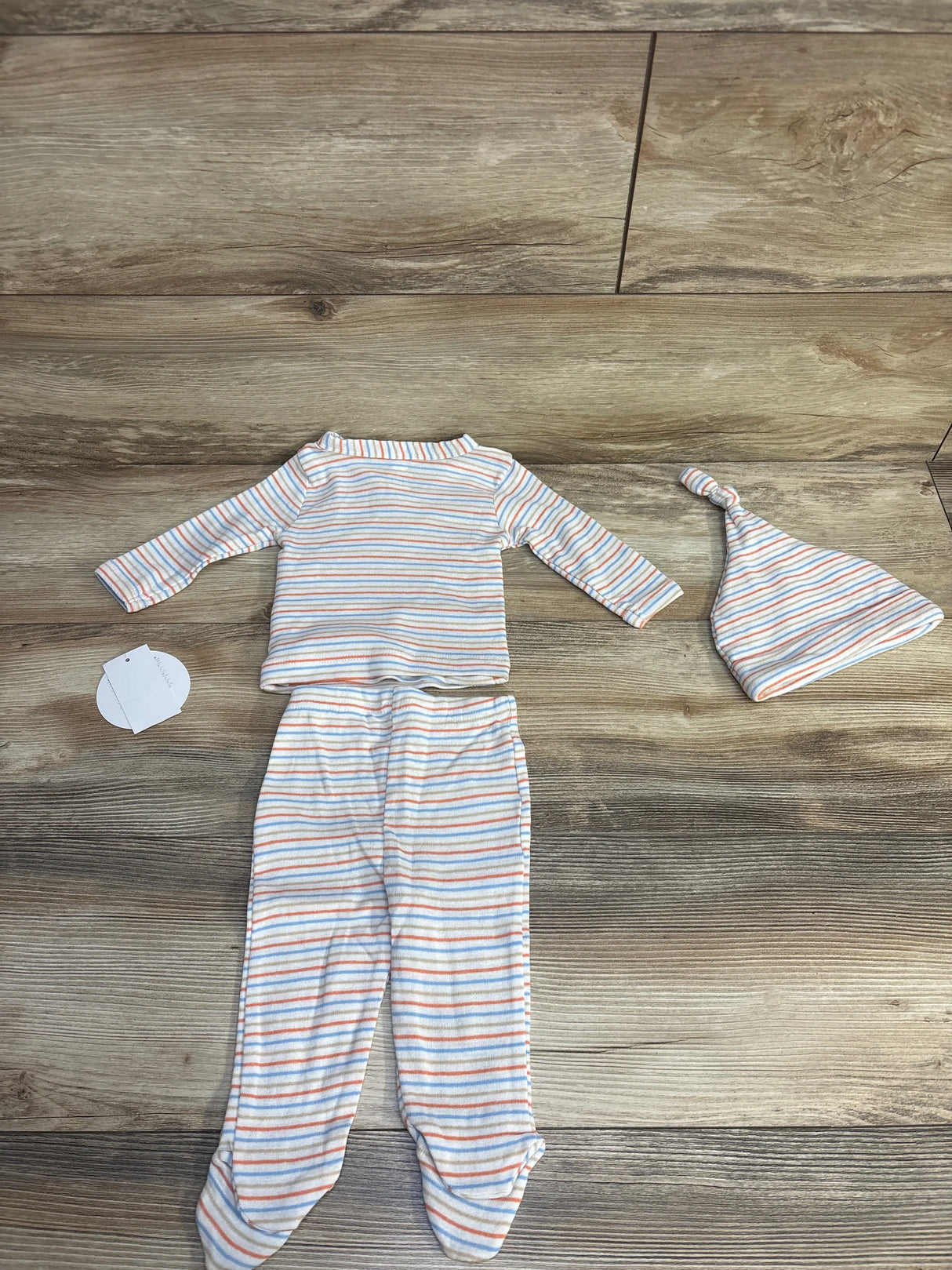 Infant striped long sleeve onesie with matching pants and knotted hat on wooden floor