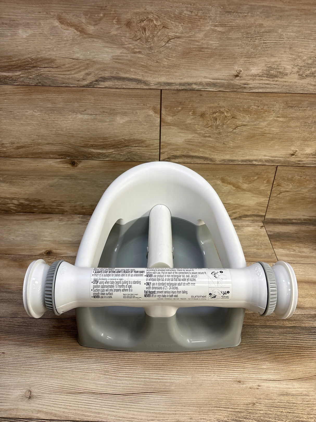 Top view of Summer Infant My Bath Seat grey showing front safety T-bar with suction cups and contoured seat on wood background