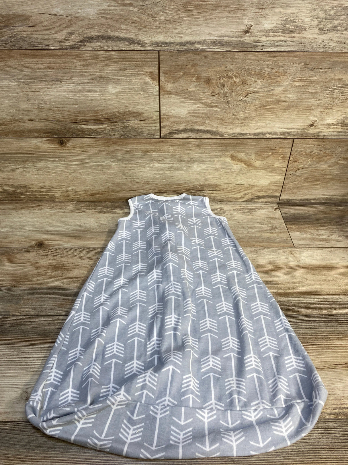 Gray sleeveless baby sleep sack with white arrow pattern on wooden background