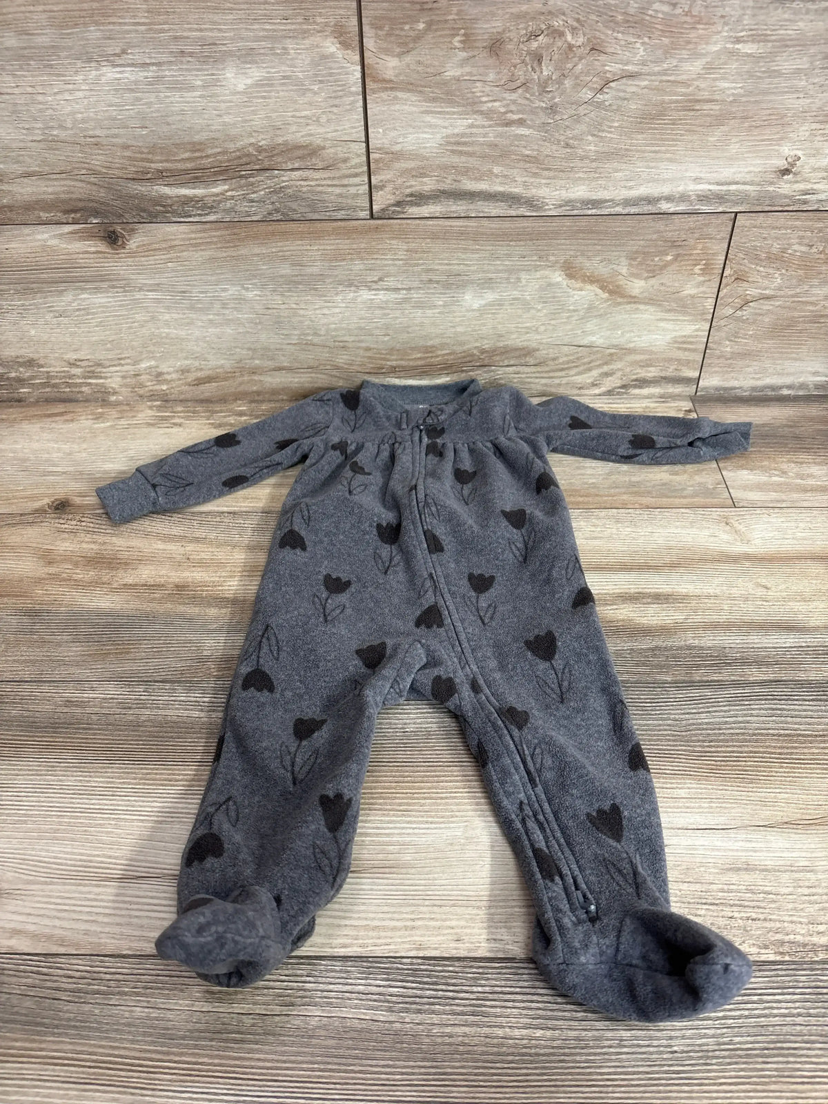 Front view of grey Carter’s footed coverall, size 9 months, showing black tulip print and front zipper on wood floor background