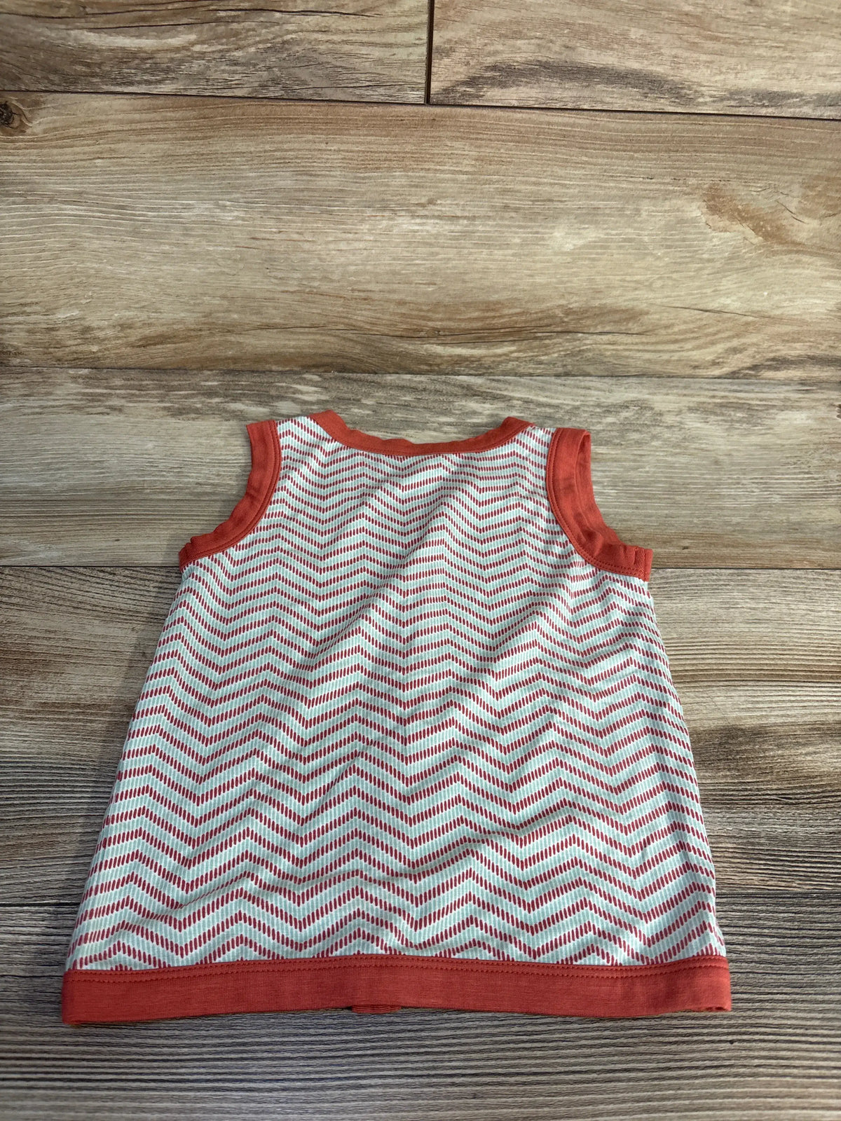 Front view of Kate Quinn bamboo button-up tank top in orange, size 18-24 months, showcasing chevron pattern on a wood background