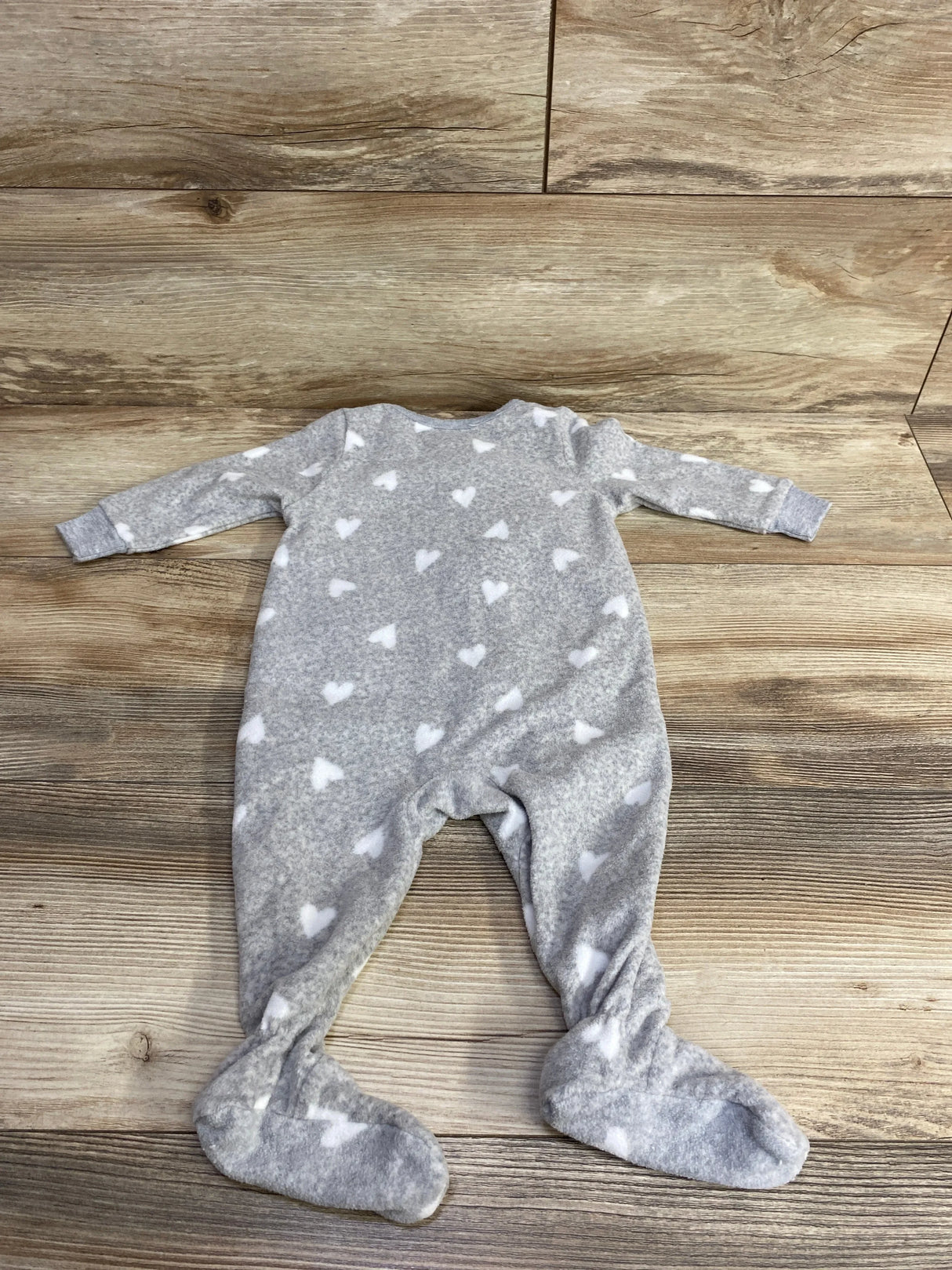 Gray baby footed sleeper with white heart pattern on wooden floor