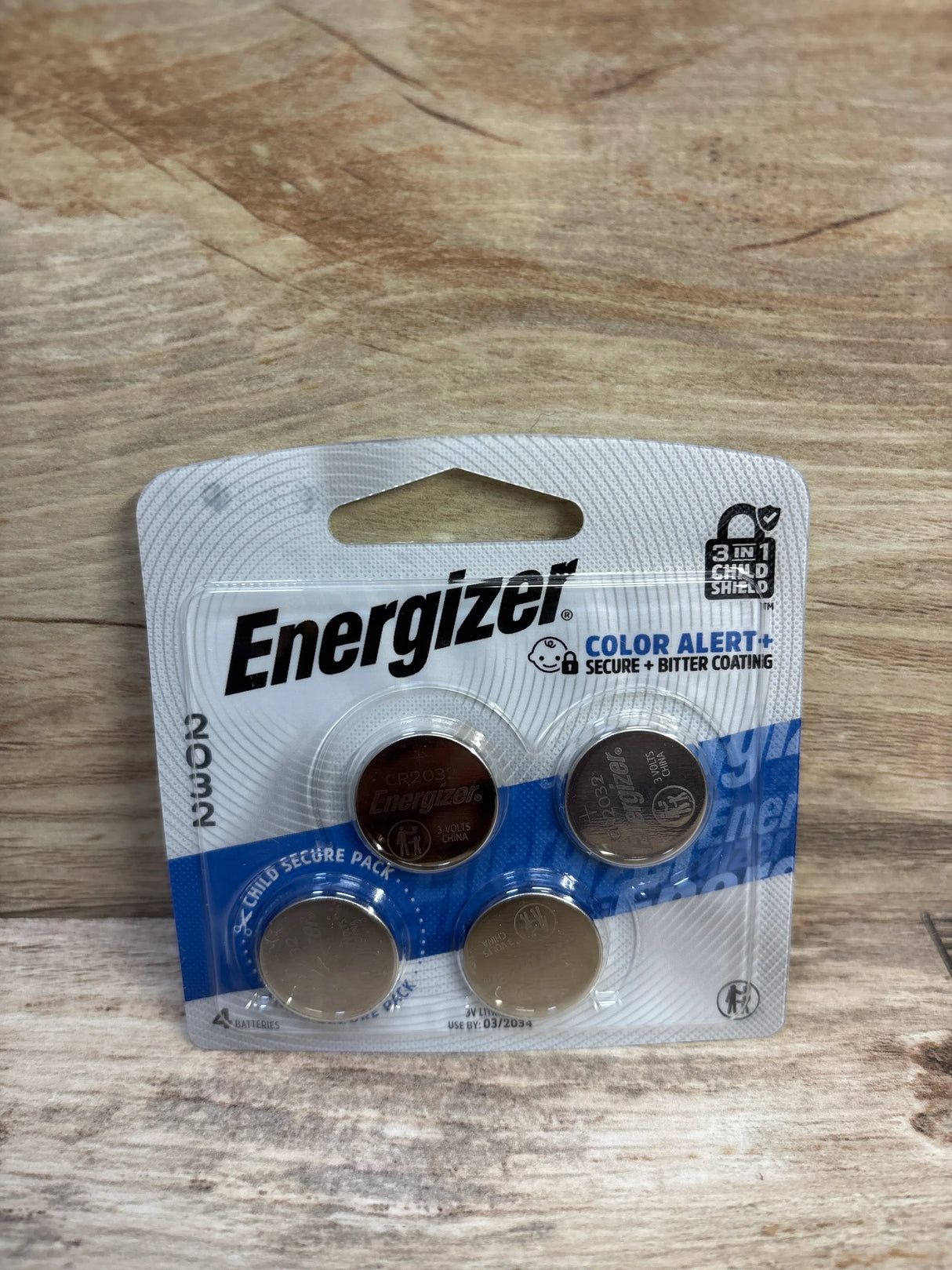 Front view of Energizer 2032 lithium coin batteries 4-pack showing brand logo and child-secure blister pack on wood background