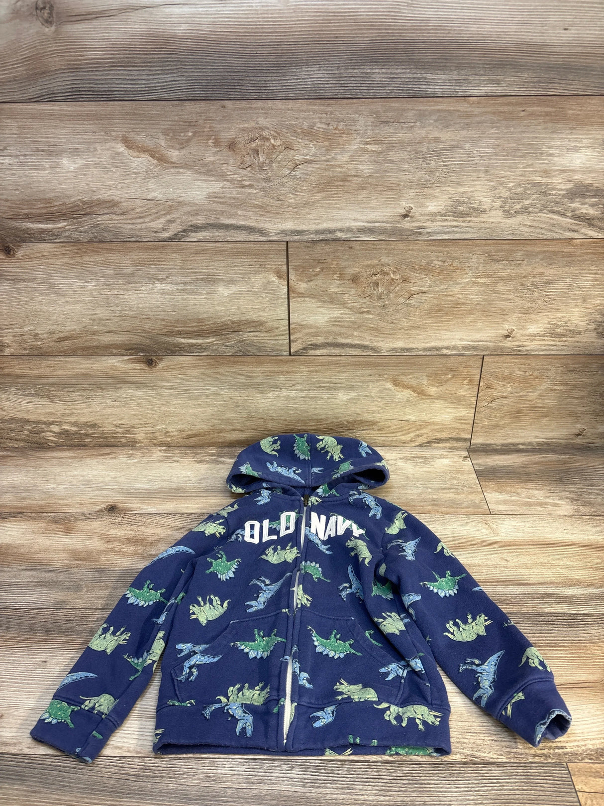 Blue Old Navy kids hoodie with green and blue dinosaur print, laid on wood floor