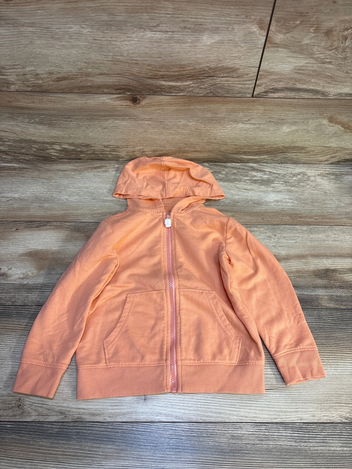 Peach kids zip-up hoodie with front pockets on wood background
