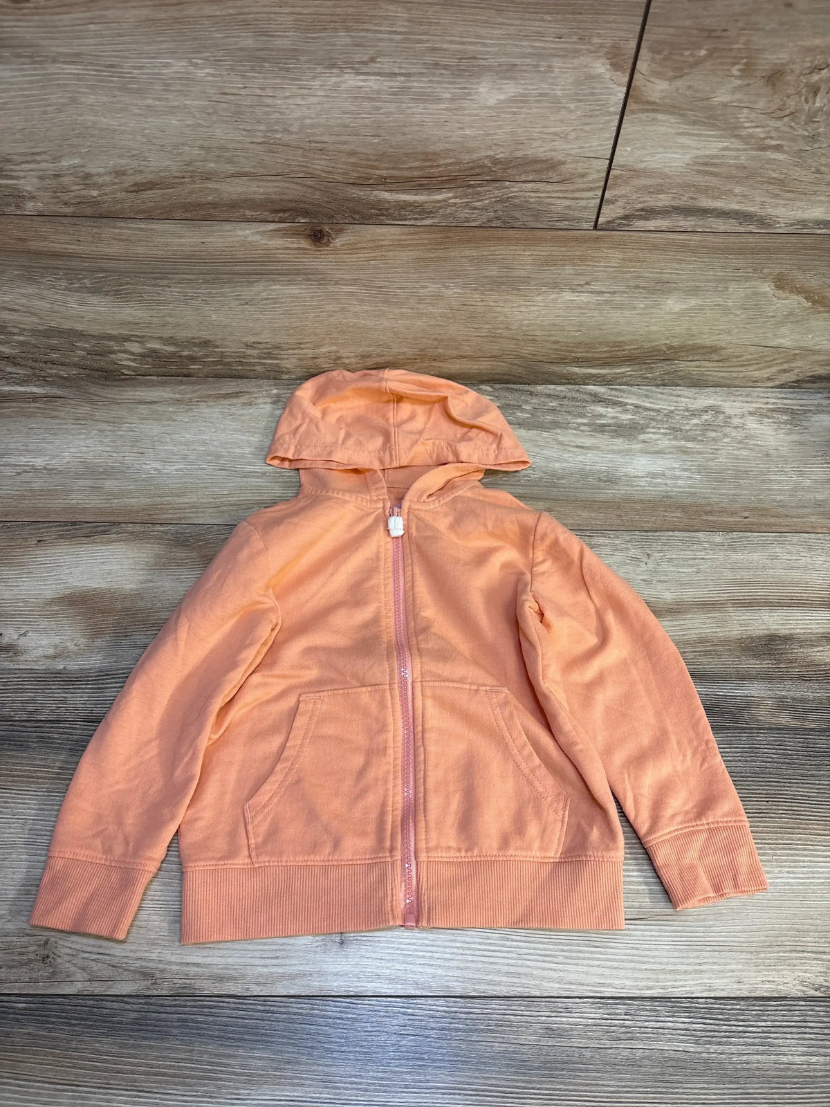 Peach kids zip-up hoodie with front pockets on wood background