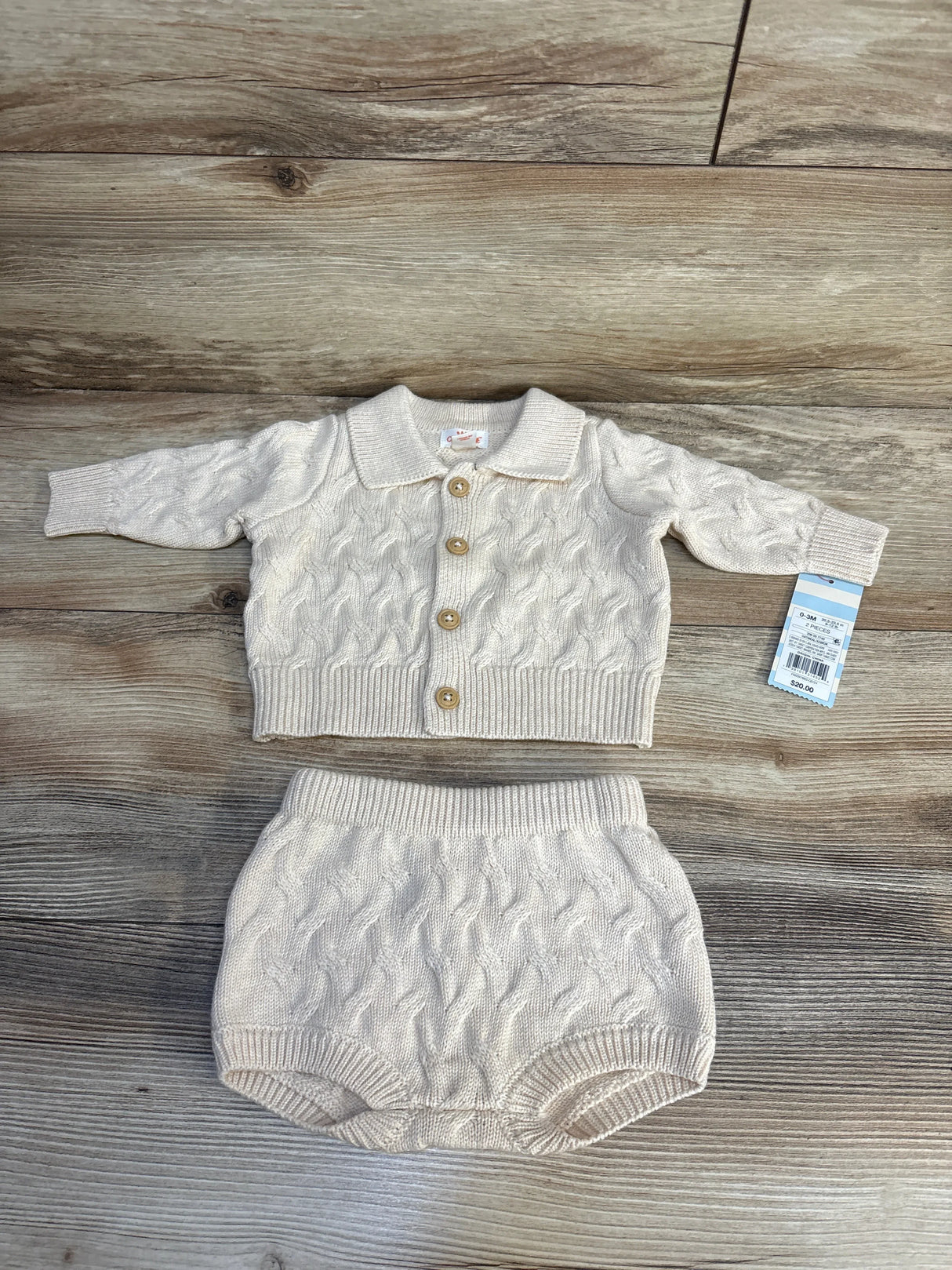 Cream cable knit baby cardigan and bloomers set, 0-3M, with wooden buttons on wood floor