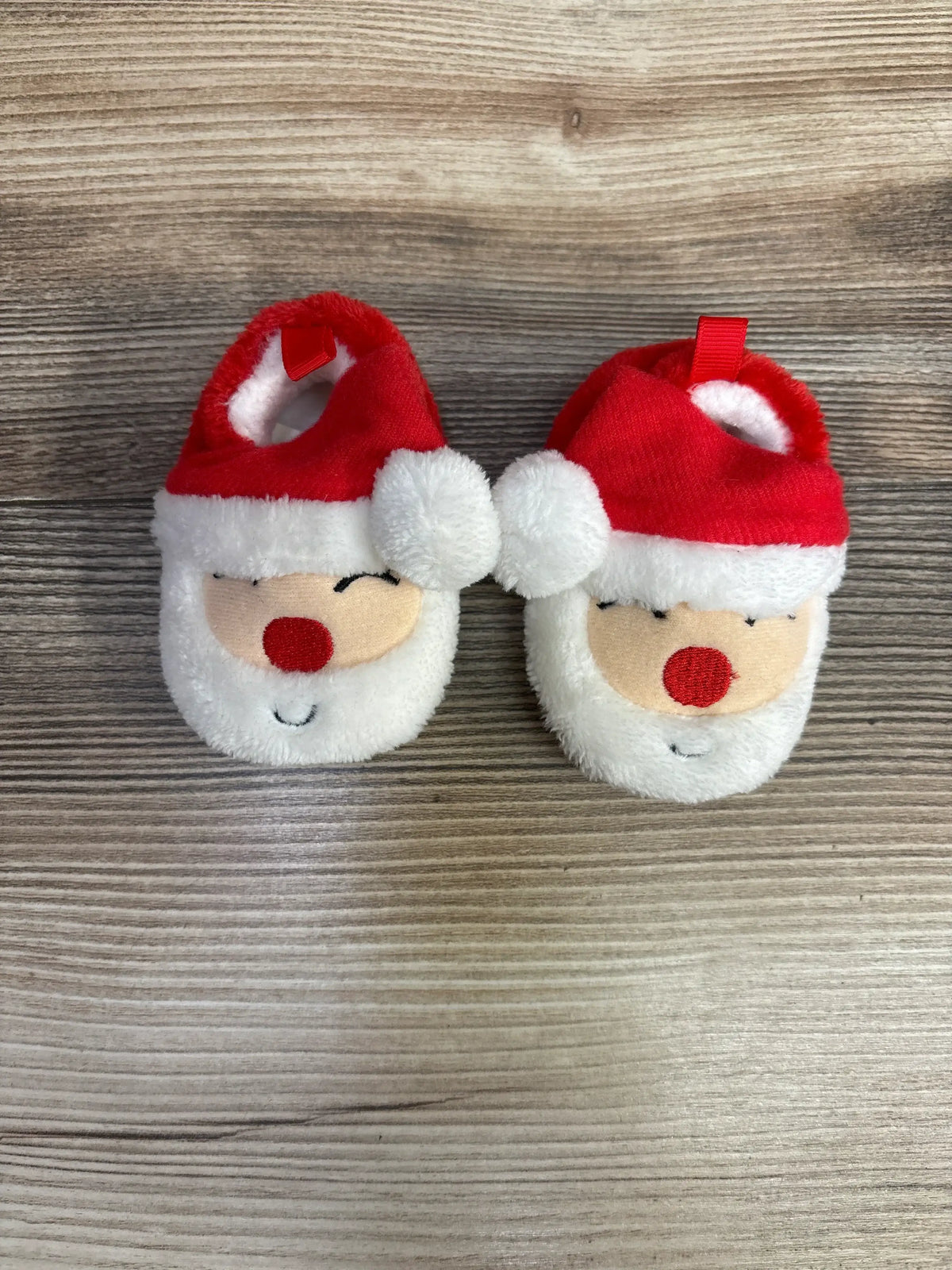 Adorable Santa-themed baby booties with red hats and white beards, perfect for holiday photos and cozy comfort.