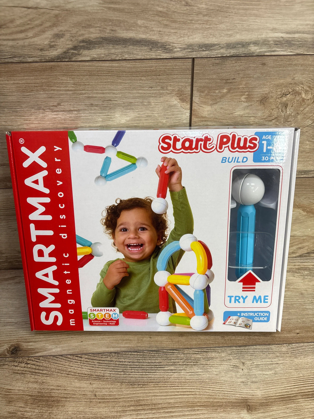 Child holding magnetic building toy SmartMax Start Plus STEM set on wood background
