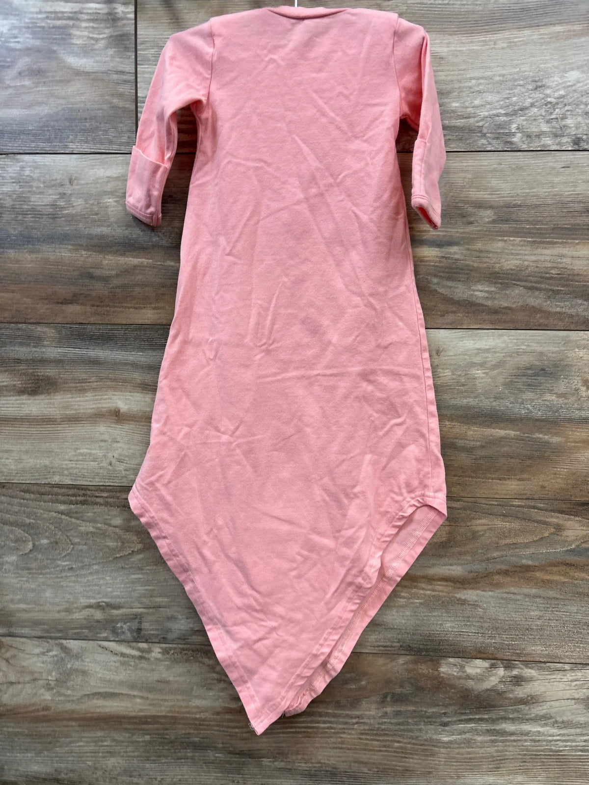 Flat lay of pink Baby Noah knotted gown (3m) showing long sleeves and pointed knotted hem on wood floor