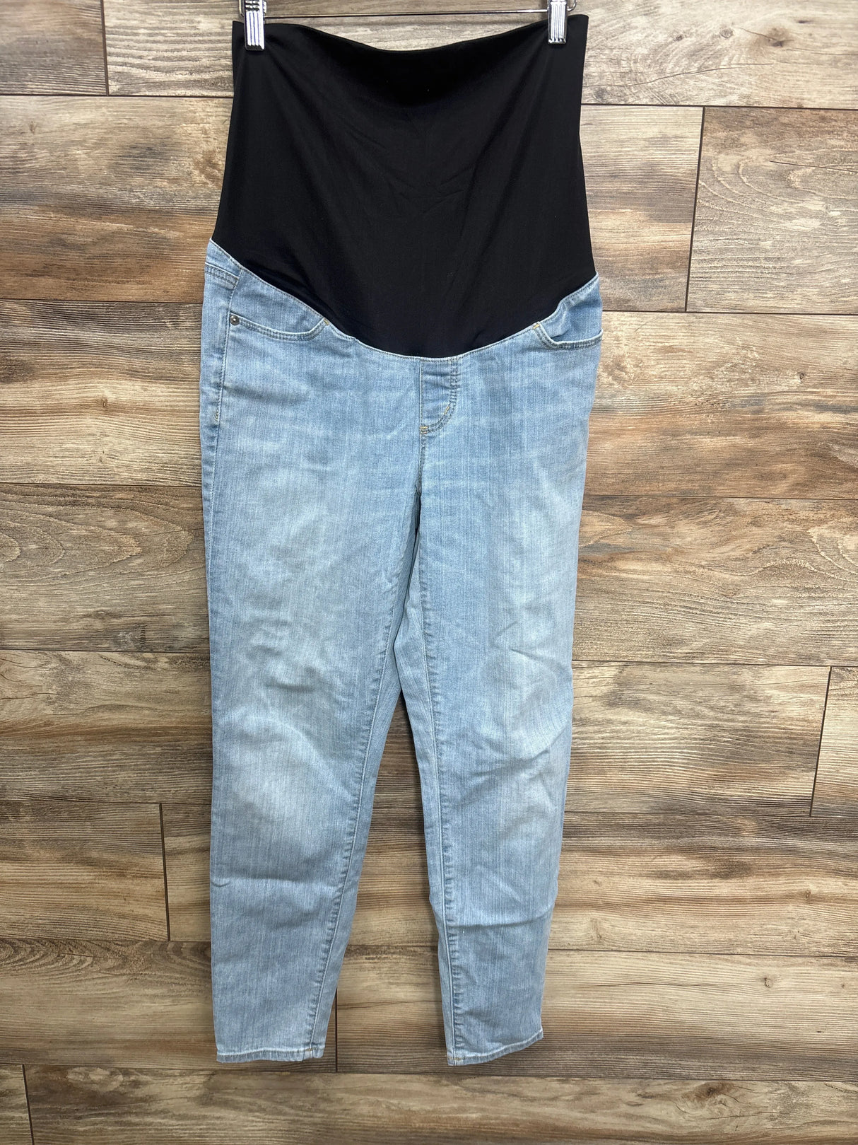 Light wash maternity jeans with black stretchy waistband hanging on wooden floor