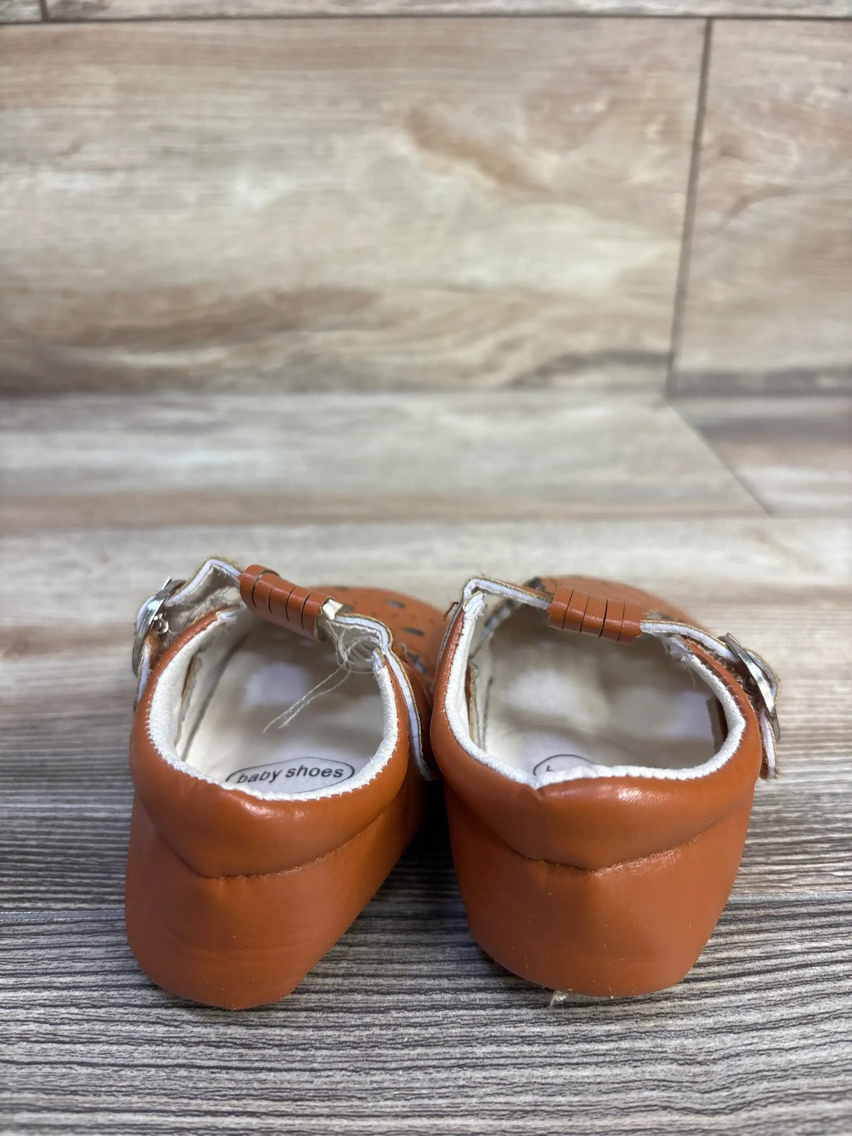 Rear view of My Little Wardrobe Sienna baby sandals showcasing buckle ankle straps and white-lined insoles on wood floor